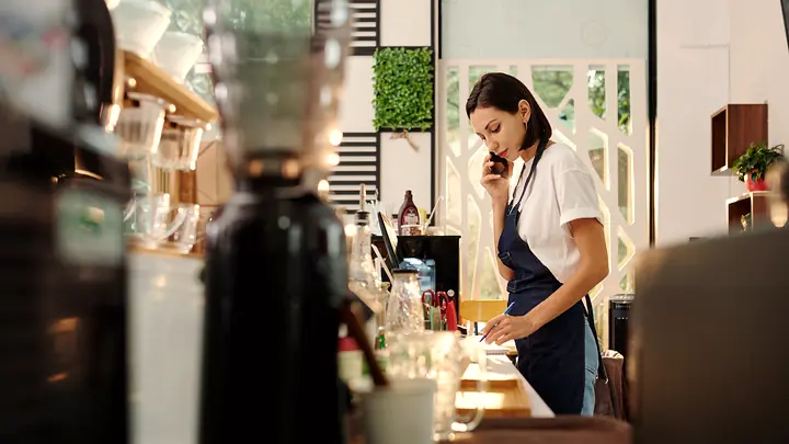 A woman on the phone behind a counter, taking notes.
