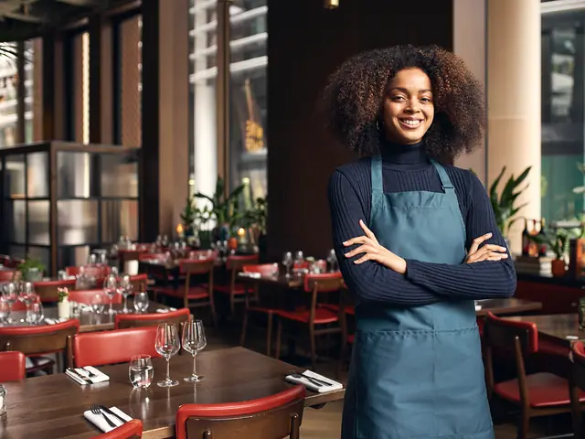 A restaurant owner in an apron smiling in her dining room.